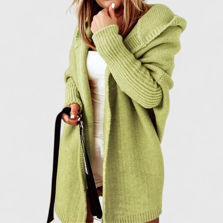 Back view of a woman walking outdoors in the yellow green Elysia hooded open front cardigan, showing the hood detail.