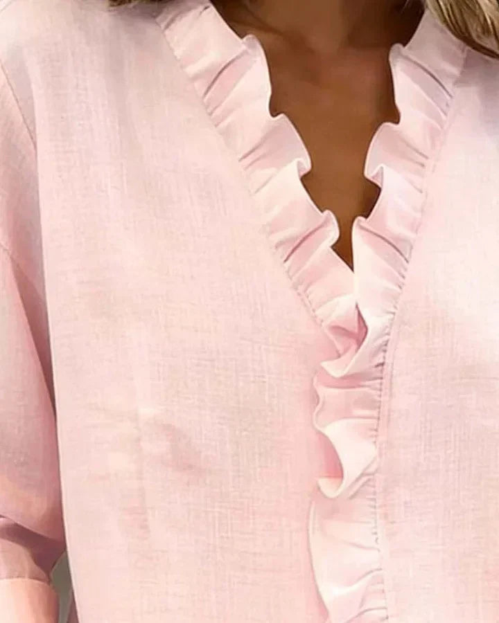 A woman adjusting the collar of her white Persephone blouse, showing its comfortable and adaptable style.