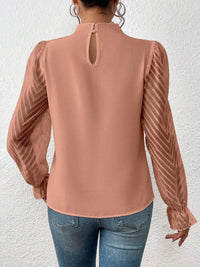 Detail of the mock neck closure on the cream ruffled mock neck blouse, focusing on the refined finish.