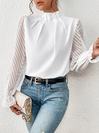 Model smiling while wearing the burnt coral ruffled mock neck blouse, conveying comfort and style.