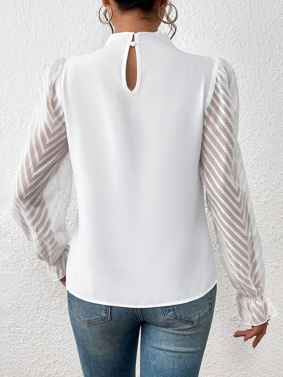 Close-up of the ruffled mock neck blouse's hemline, showing the stitching and fabric drape.