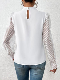 Close-up of the ruffled mock neck blouse's hemline, showing the stitching and fabric drape.