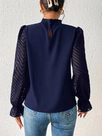 Side profile of the navy ruffled mock neck blouse, highlighting the flounce sleeves and semi-sheer texture.