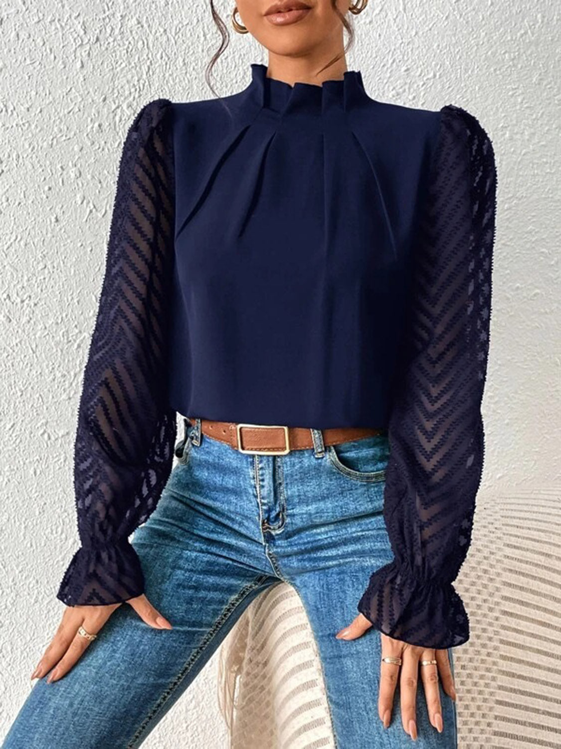 Close-up of the mock neck and ruffled detail on the black blouse, showing the fabric quality.