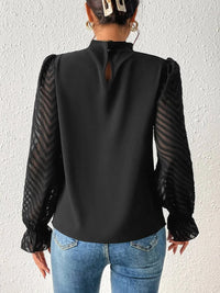 Detail shot of the sleeve cuff and ruffle on the cream blouse, emphasising the design elements.