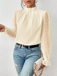 Flat lay of the navy ruffled mock neck blouse, folded neatly to show the full garment's shape.