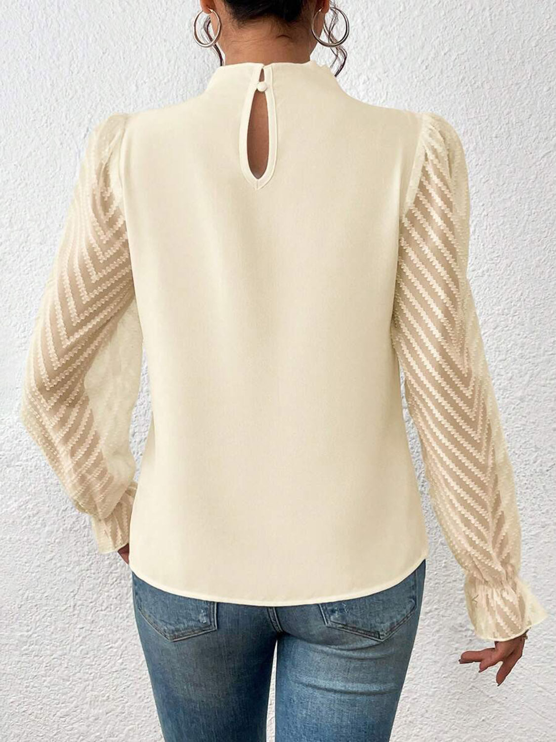 Model posing with the burnt coral ruffled mock neck blouse, showing its flow and movement.