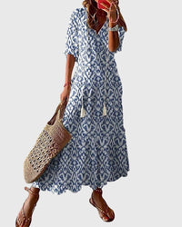Front view of a woman wearing a blue Anthea boho vintage summer dress, standing in a sunny outdoor setting.