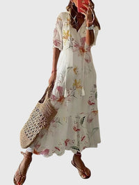 Woman relaxing outdoors in a floral Anthea boho vintage summer dress, enjoying the summer breeze.