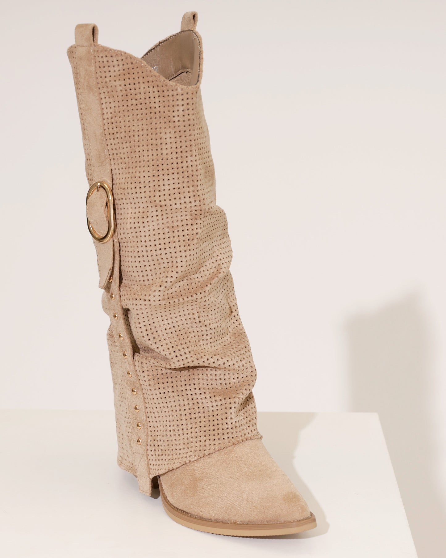 Side profile of a taupe cowboy boot, highlighting the intricate perforations and stacked block heel.