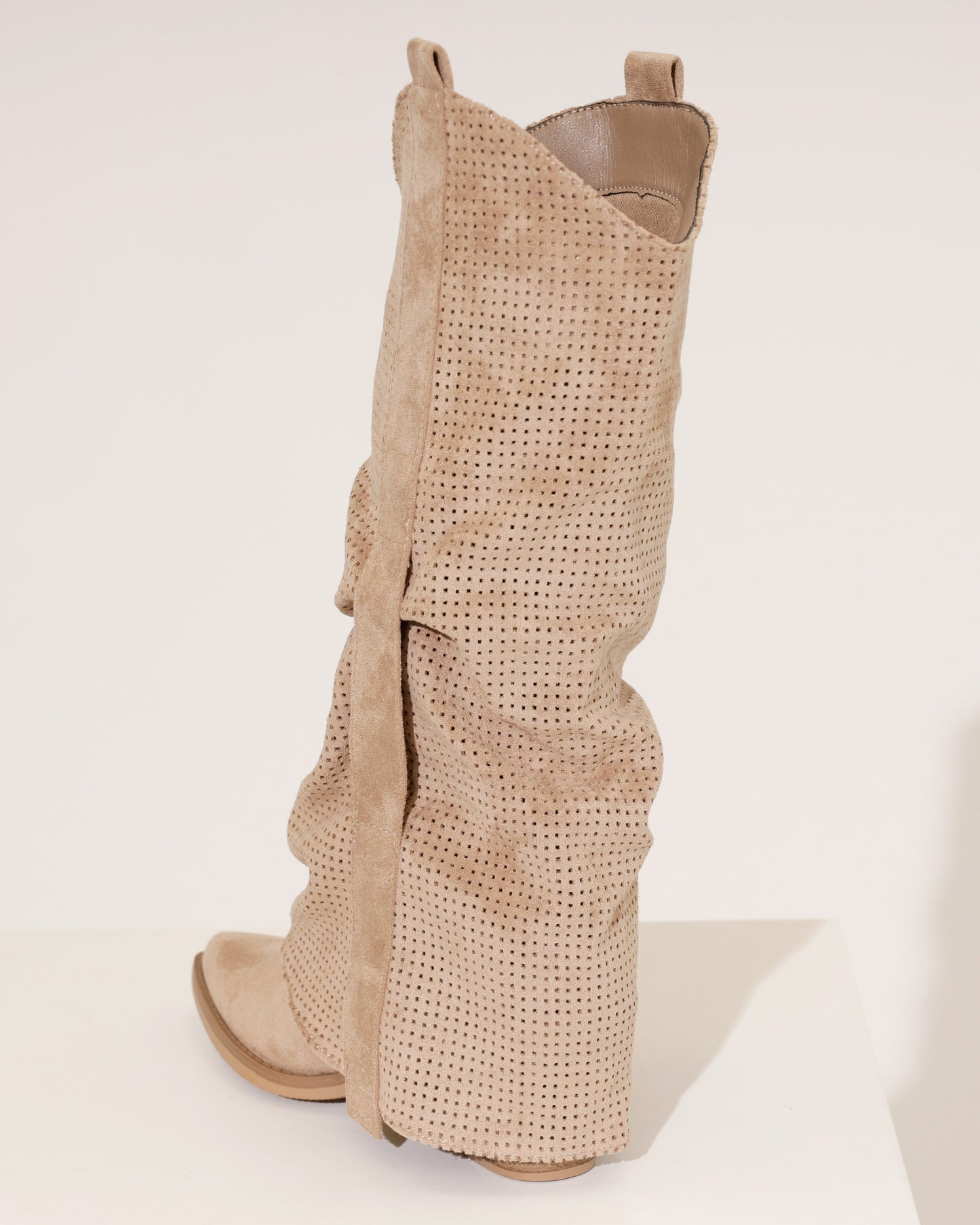 Lifestyle shot of a woman wearing taupe perforated cowboy boots with a flowing dress, in an outdoor setting.