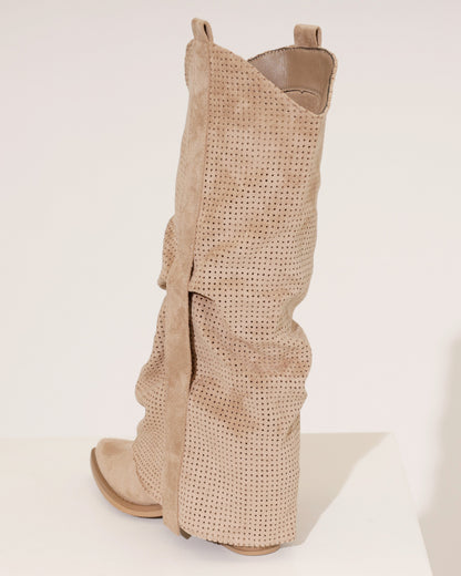 Lifestyle shot of a woman wearing taupe perforated cowboy boots with a flowing dress, in an outdoor setting.