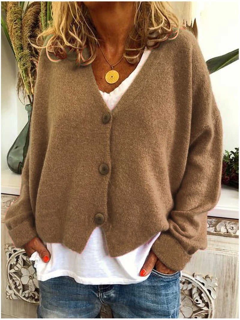 A khaki Calypso V-neck button cardigan draped over a chair, emphasising its relaxed and comfortable appeal.