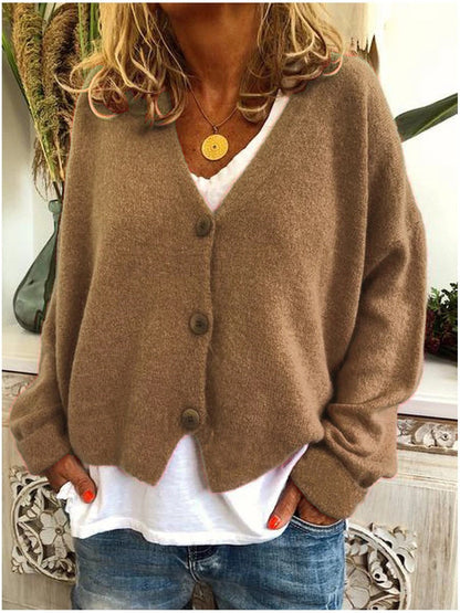 A khaki Calypso V-neck button cardigan draped over a chair, emphasising its relaxed and comfortable appeal.