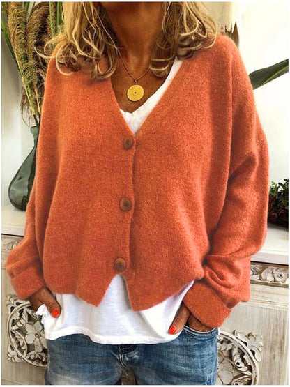Close-up of the V-neckline and button-front closure on a brown orange Calypso cardigan, highlighting button details.