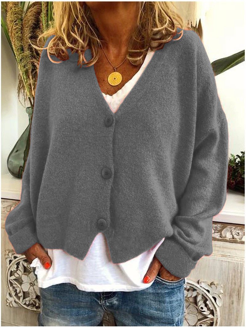 A grey Calypso V-neck button cardigan styled open over a top, demonstrating its versatile layering capability.