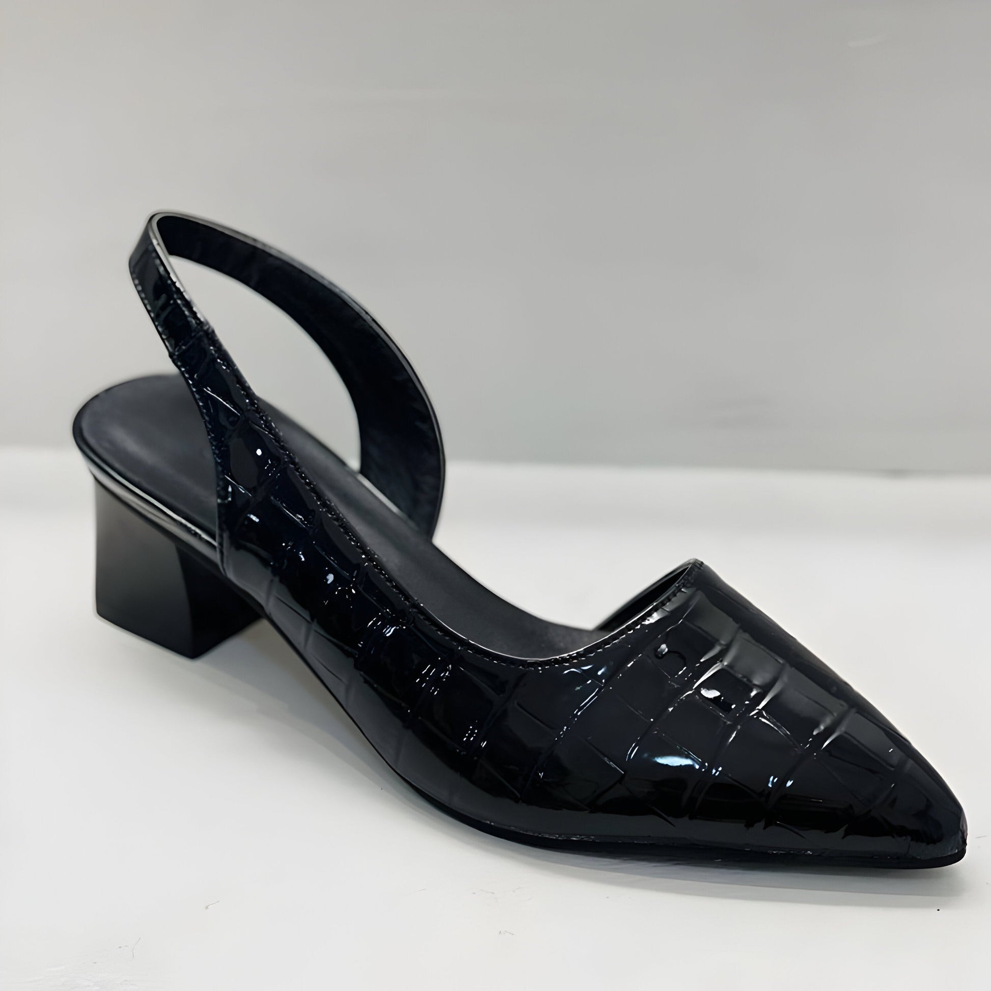 A woman wearing black orthopaedic comfortable heels, standing confidently in a professional setting.