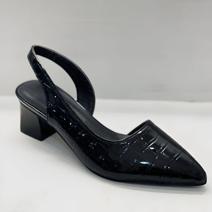 A woman wearing black orthopaedic comfortable heels, standing confidently in a professional setting.