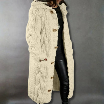 Woman fastening the easy-to-fasten buttons on the front of the elegant cable knit longline coat.
