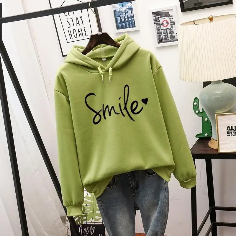 Lifestyle shot of a woman comfortably lounging in the green Cleo comfort hoodie, enjoying a casual moment.
