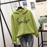 Lifestyle shot of a woman comfortably lounging in the green Cleo comfort hoodie, enjoying a casual moment.