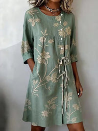 Front view of the Seraphina floral summer dress in a vibrant green, showcasing the round neck and wrap-tie detail.