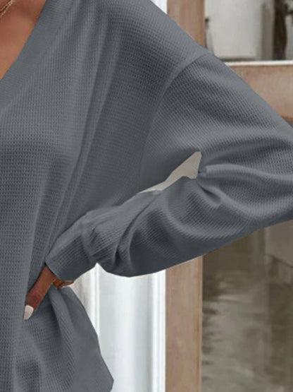 Close-up of the dark grey waffle-knit fabric, highlighting the quality and construction of the blouse.