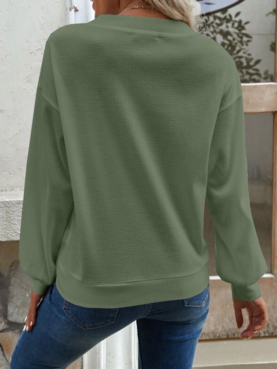 Detail of the matcha green Elowen blouse's V-neck, illustrating its clean and simple line.