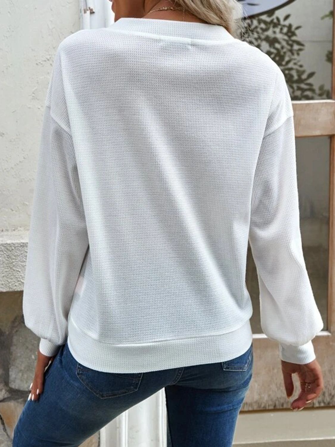 Side profile of the white Elowen blouse, highlighting the dropped shoulder and regular sleeve length.