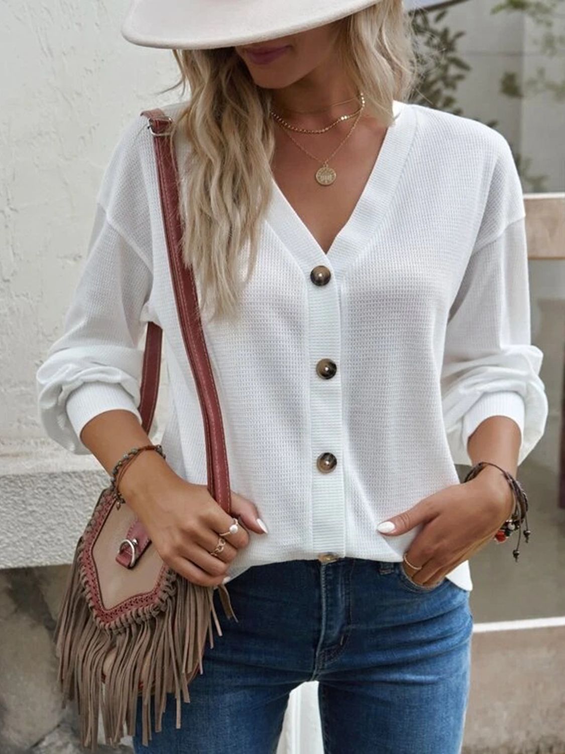 Close-up detail of the waffle-knit fabric on the white V-neck blouse, showing its intricate texture.