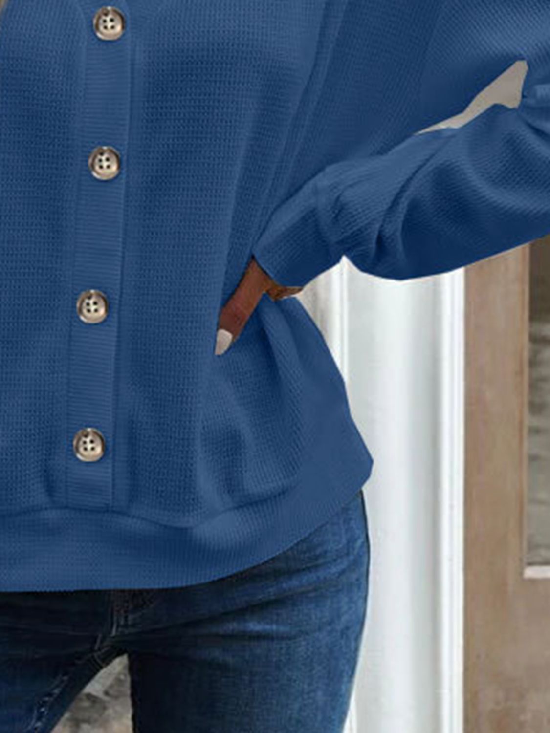 Close-up of the sleeve cuff on the blue waffle-knit blouse, showing the neat finishing.