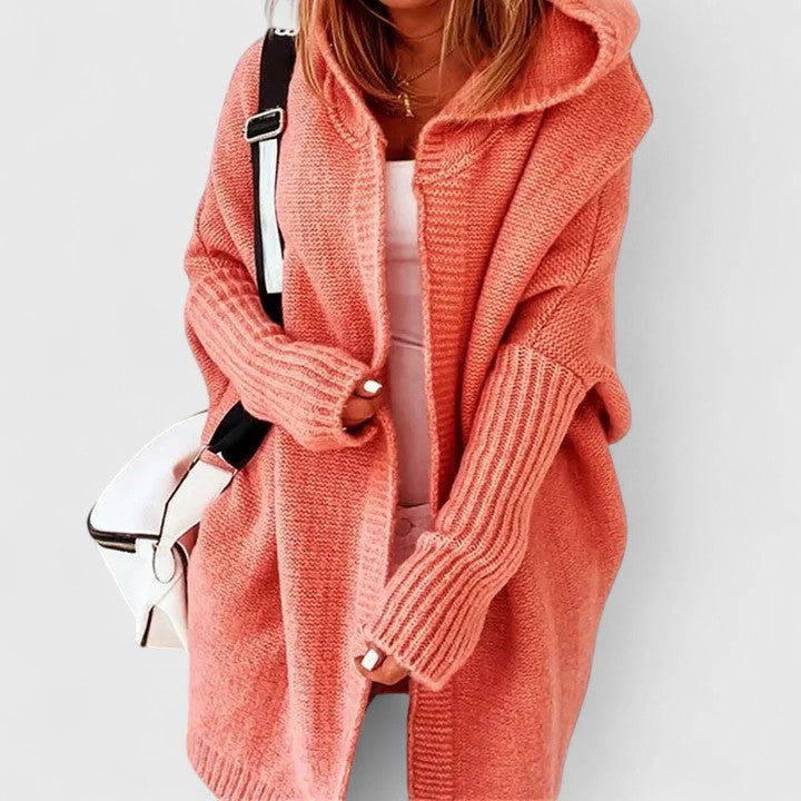 Close-up detail of the textured knit fabric and ribbed cuff on the sleeve of the Elysia cardigan in orange.