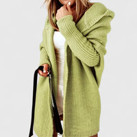 Back view of a woman walking outdoors in the yellow green Elysia hooded open front cardigan, showing the hood detail.