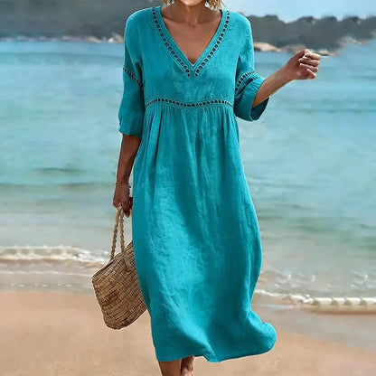Lifestyle shot of a woman enjoying a beach setting while wearing the lake blue Inès embroidered V-neck dress.