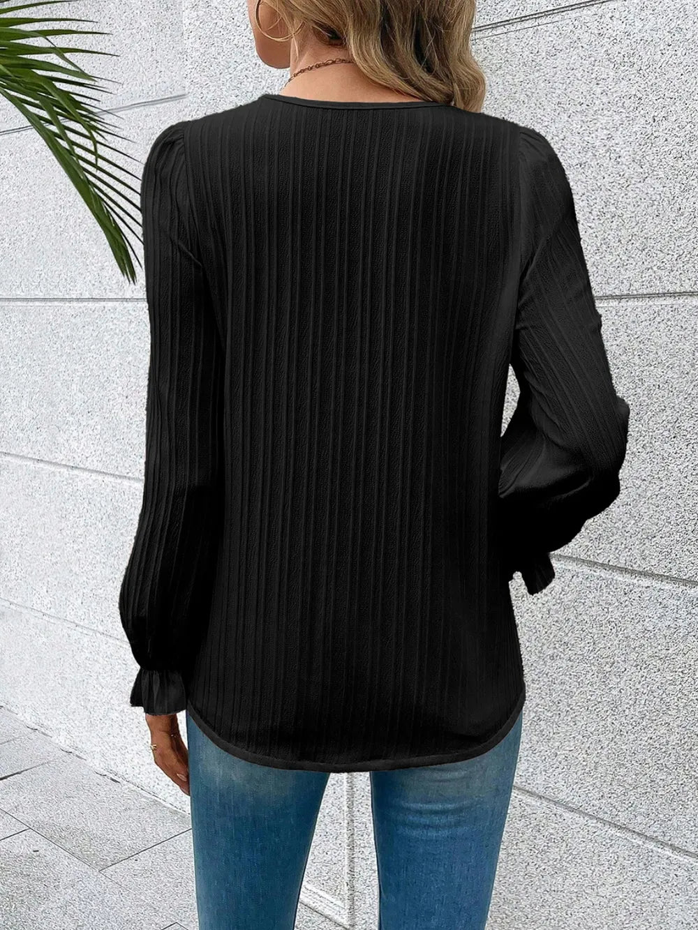 The Seraphine elegant V-neck lace detail blouse in classic black, hanging freely to show its full length.