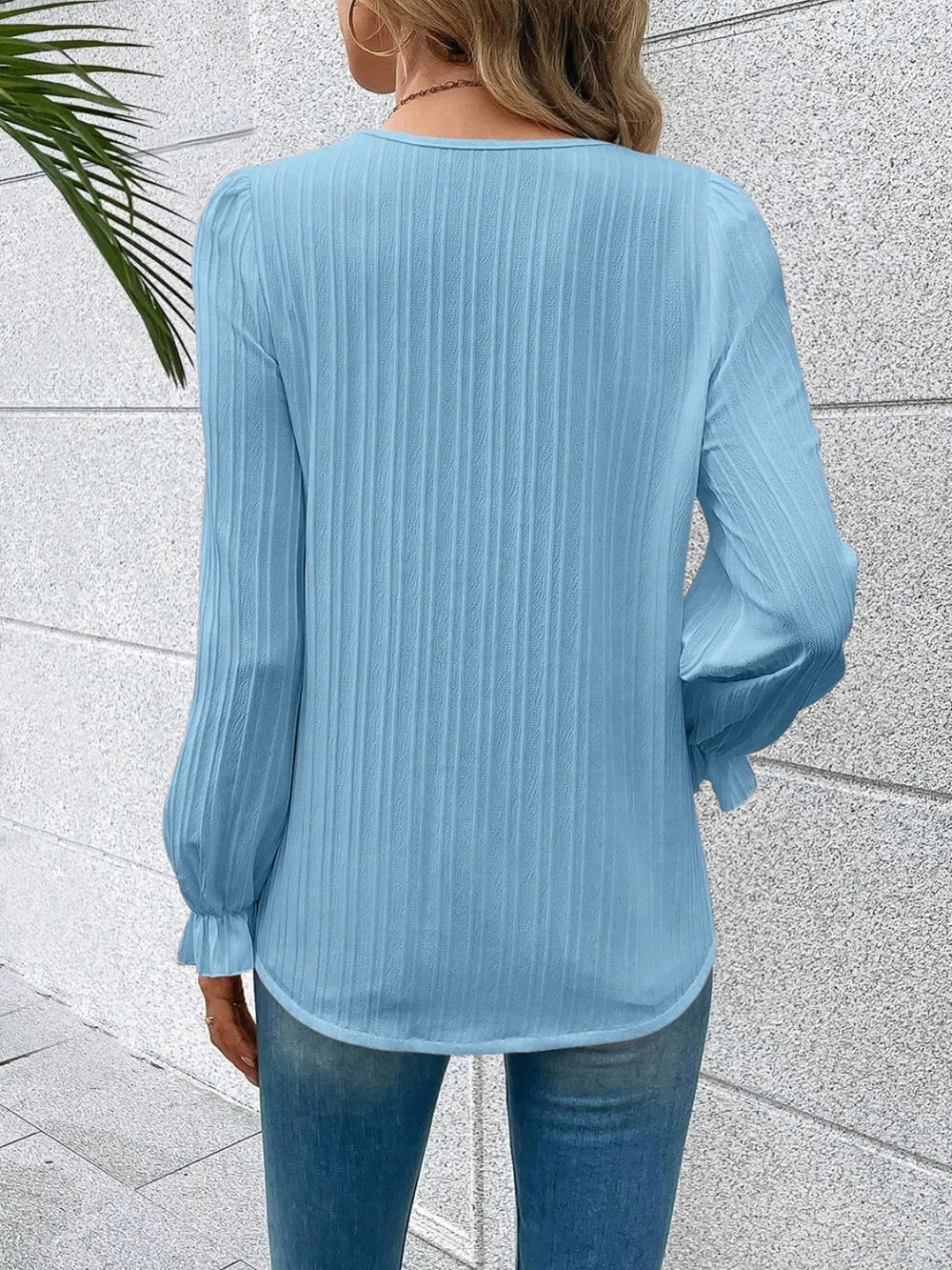 The Seraphine elegant V-neck lace detail blouse in sky blue, presented neatly folded on a flat surface.