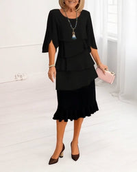 Side profile of the black Serena elegant comfort ruffle dress, showcasing the flowing midi length and split sleeves.