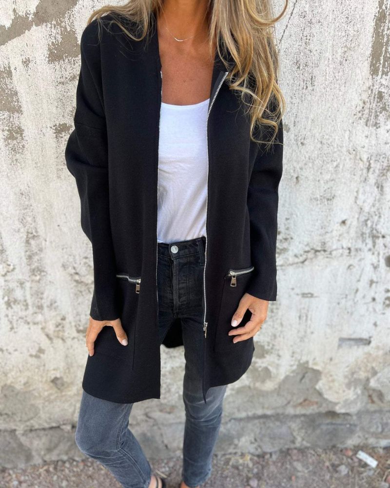 Side profile of a woman wearing a black hooded longline cardigan, highlighting the length and drape of the garment.