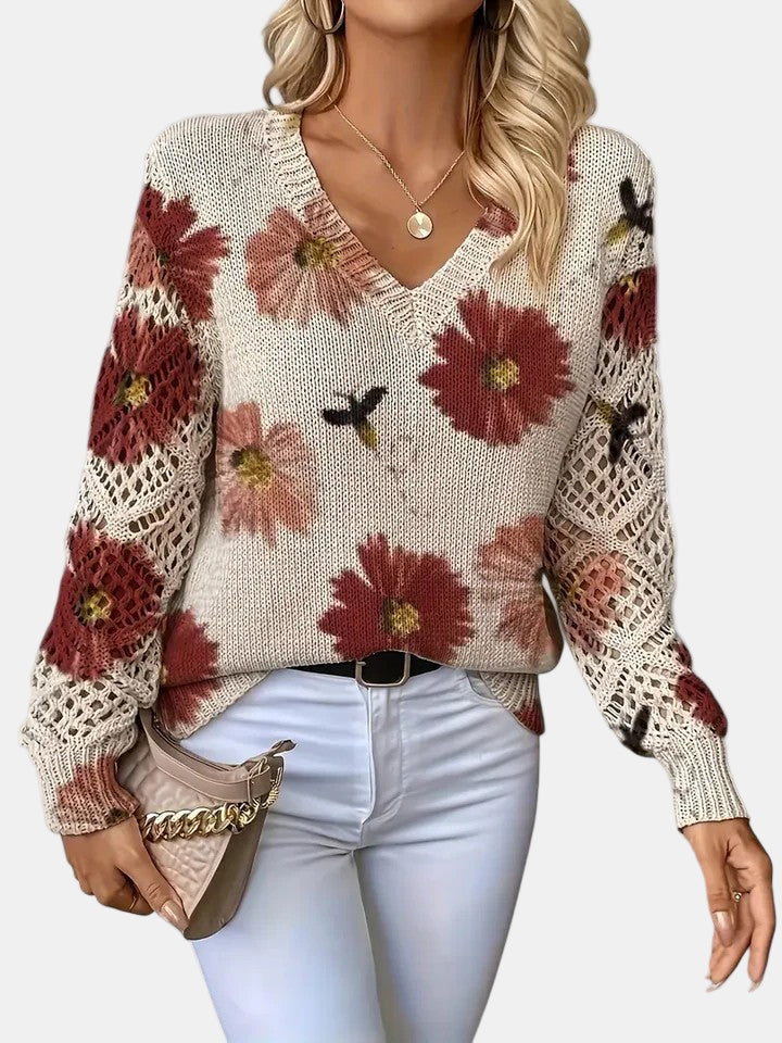 Close-up detail of the open-knit sleeve on a red floral knit sweater, highlighting the texture.