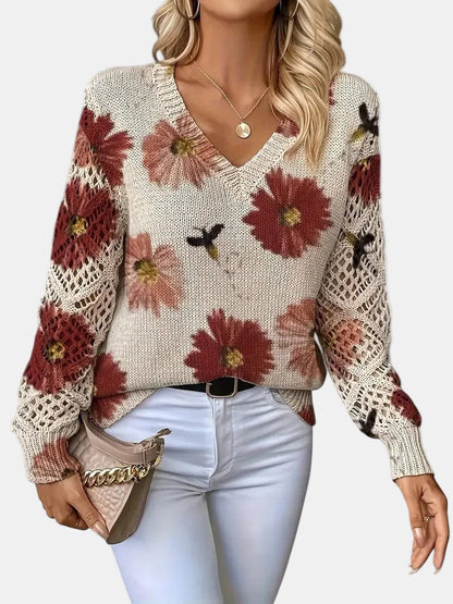 Close-up detail of the open-knit sleeve on a red floral knit sweater, highlighting the texture.