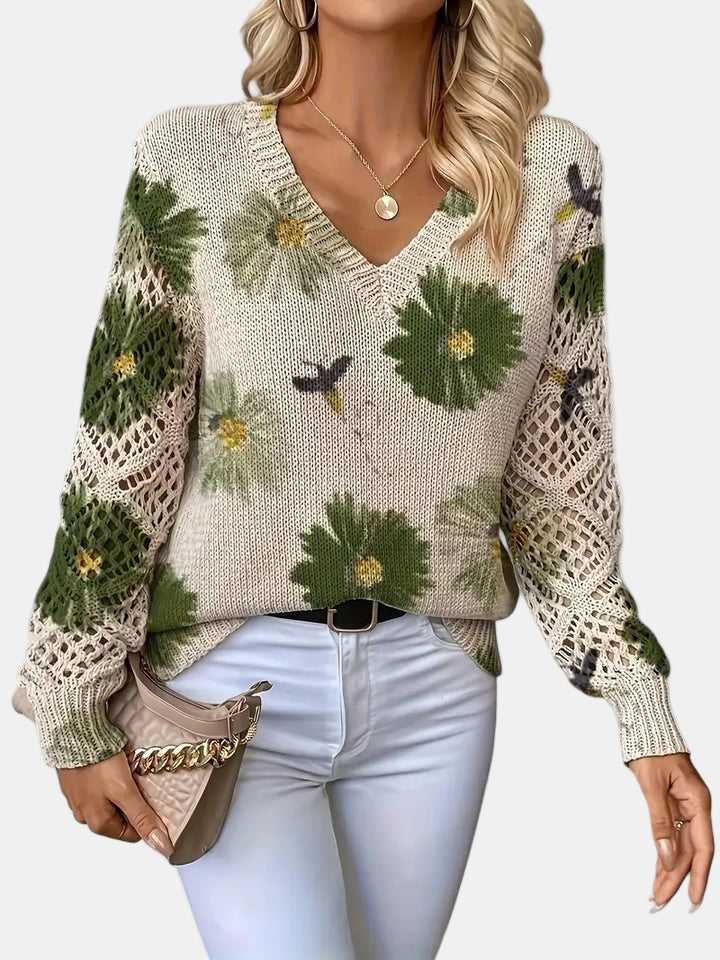 Stylish woman wearing a green floral knit V-neck sweater with jeans, posing casually outdoors.