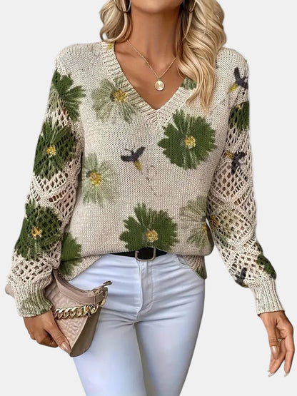 Stylish woman wearing a green floral knit V-neck sweater with jeans, posing casually outdoors.