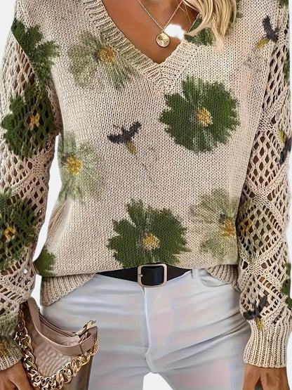Woman enjoying a coffee while wearing a purple floral knit V-neck sweater, lifestyle shot.