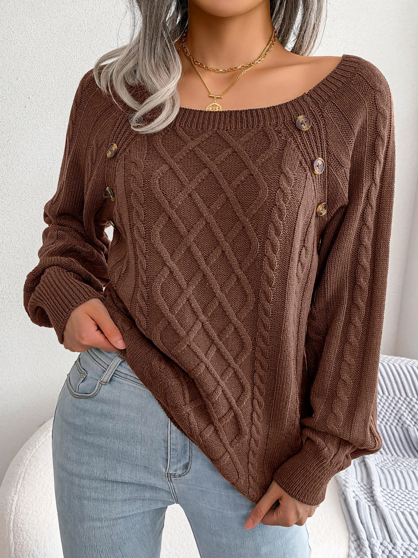 An army green casual knitted sweater draped over a chair, emphasising its breathable material.