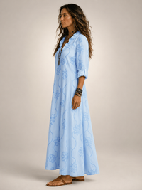 Front view of a woman wearing the white Lotte floral flowing maxi dress, in a bright outdoor setting.