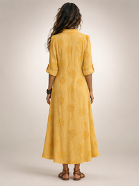 Close-up detail of the embroidered floral pattern on the yellow Lotte flowing maxi dress fabric.
