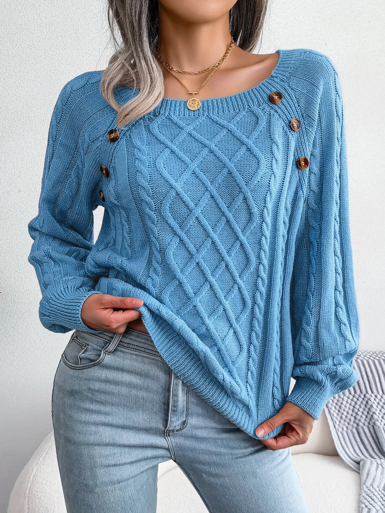 Detailed shot of the unique button design on the shoulder of the khaki knitted sweater.