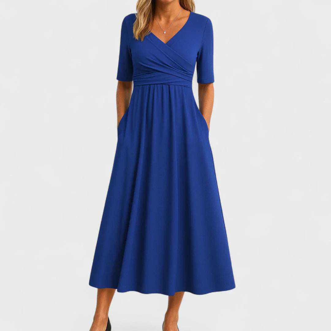 Side profile of a woman in the green Lynton elegant midi dress, highlighting the gentle flare of the skirt and elbow-length sleeves.