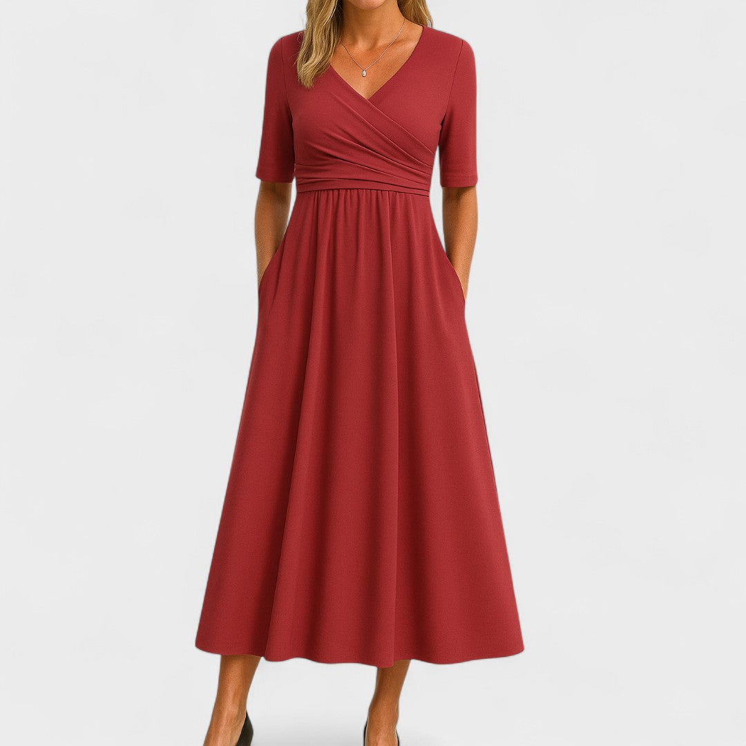 Woman comfortably seated, showcasing the practical side pockets of the red Lynton elegant midi dress.
