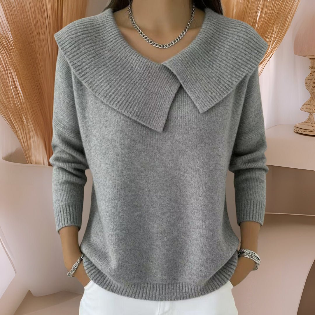 Overhead view of a grey knitted soft collar sweater, folded to show off its luxurious softness and quality.